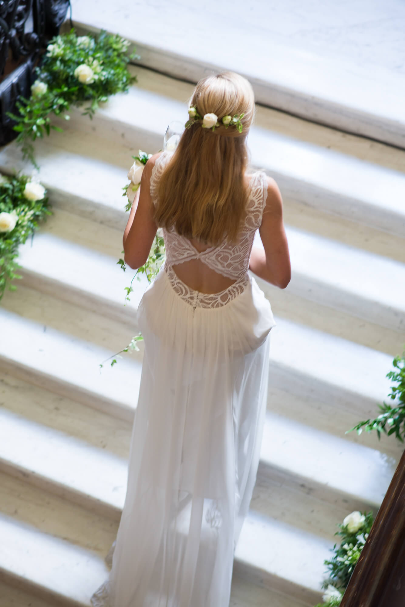 A bride on the steps of Dartmouth house showing the back detail of her wedding dress by Fairytale London